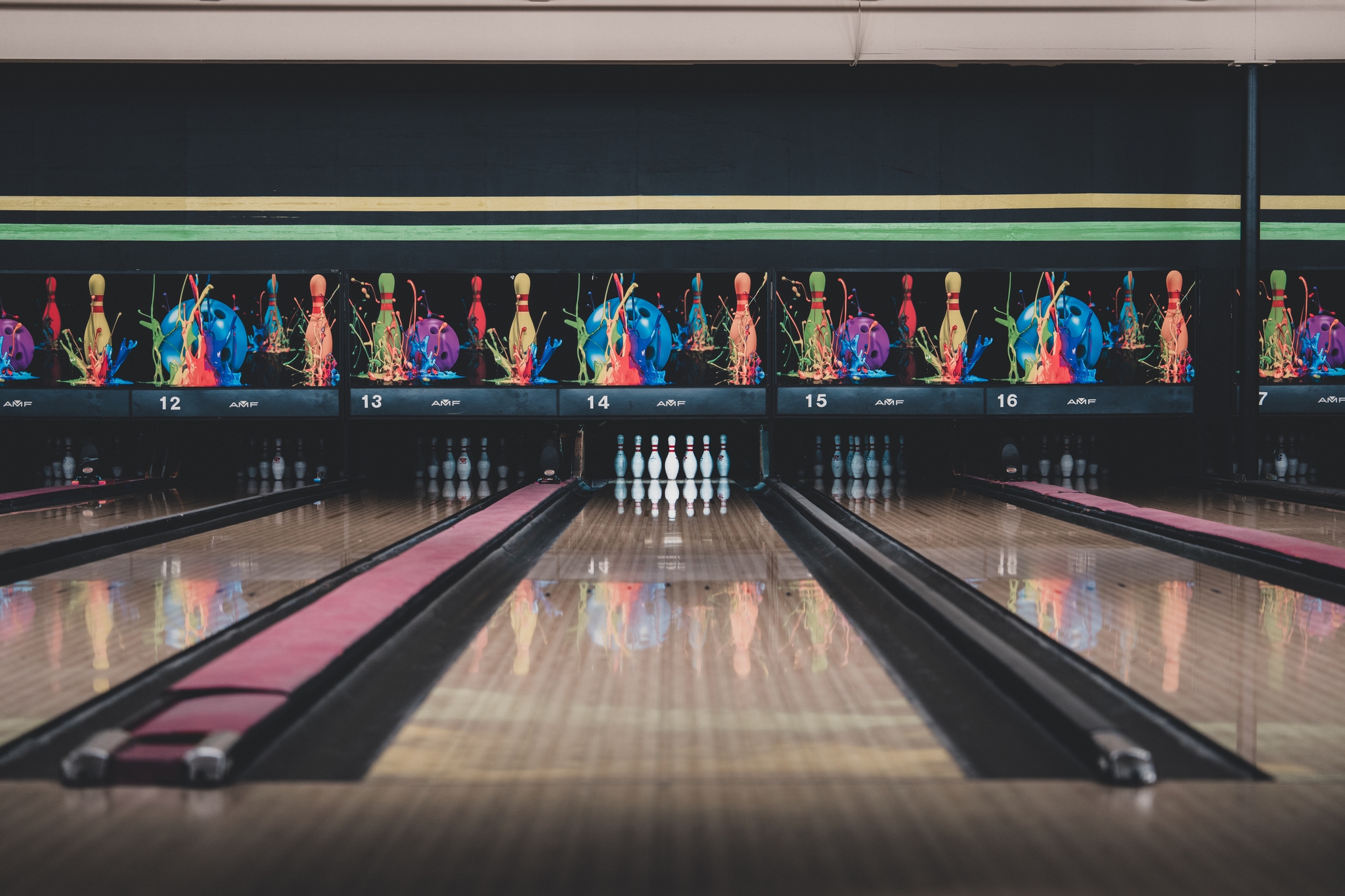 A bowling alley with multiple lanes, featuring colorful bowling pins arranged at the end of each lane
