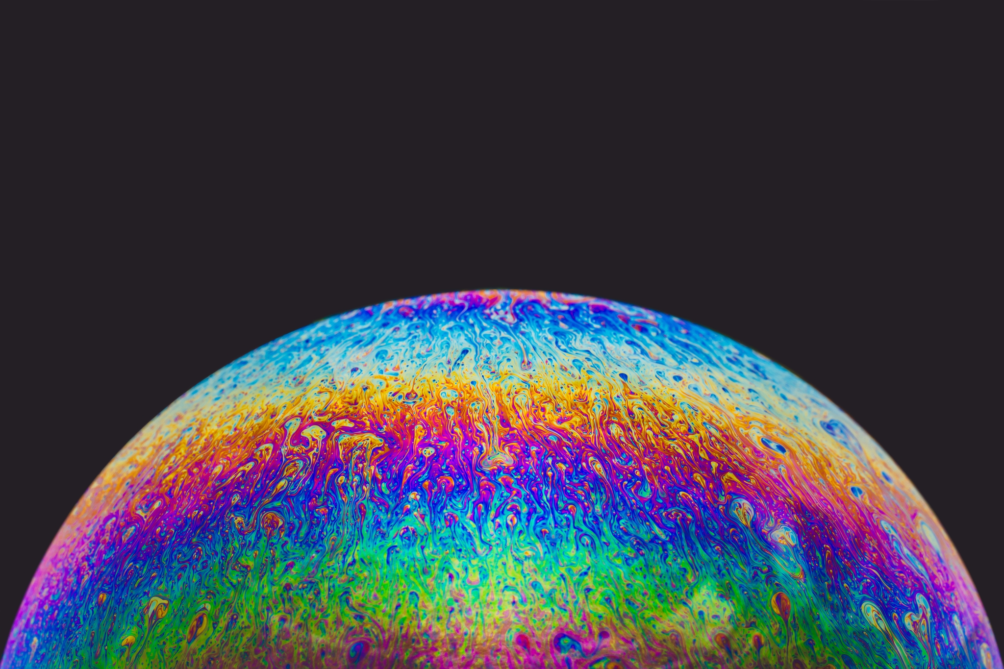 A colorful, iridescent surface resembling a soap bubble against a dark background