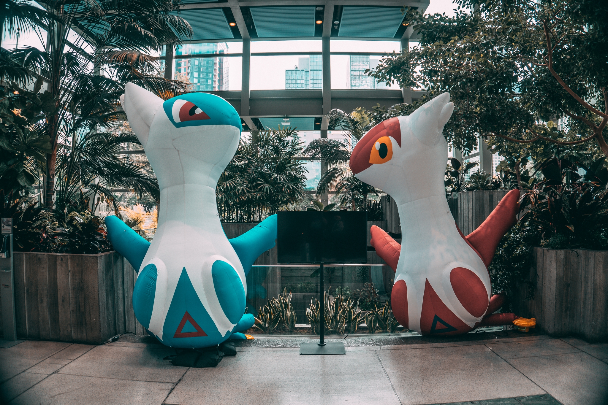 Two large Pokemon sculptures in a garden setting within a modern building