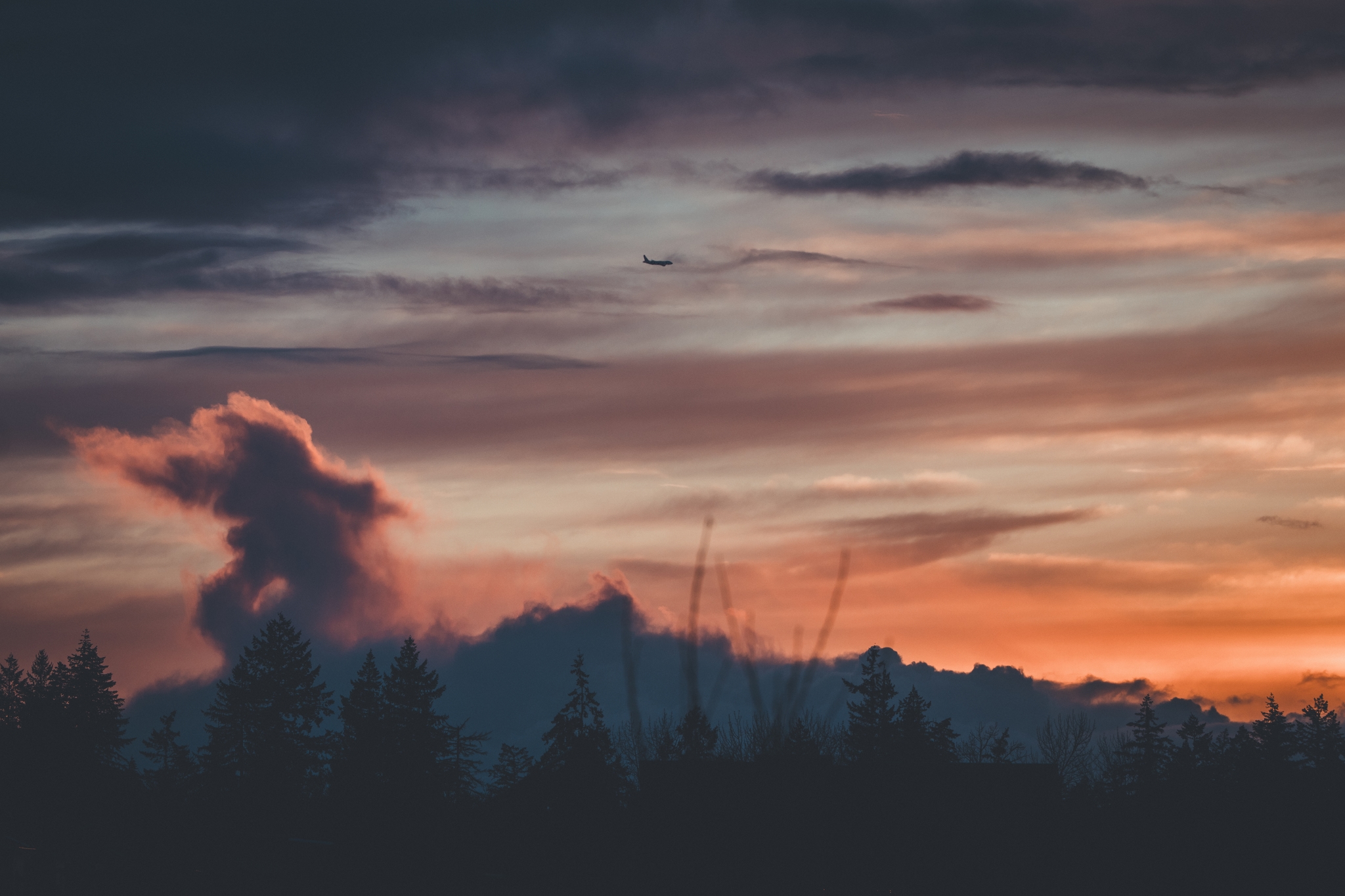 A dramatic sunset with dark clouds and a silhouette of trees on the horizon