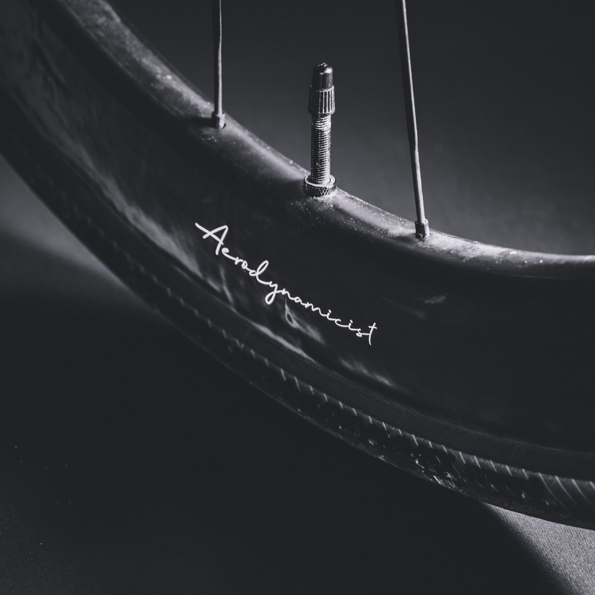 A close-up of a bicycle wheel with a visible valve stem and a signature on the tire