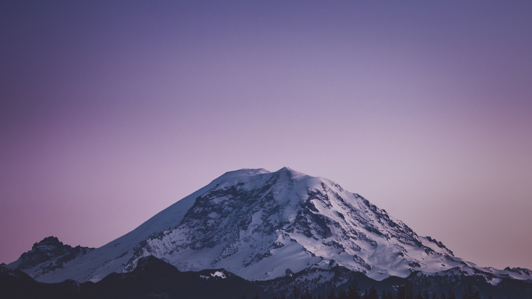 A snow-capped mountain under a purple sky at dusk