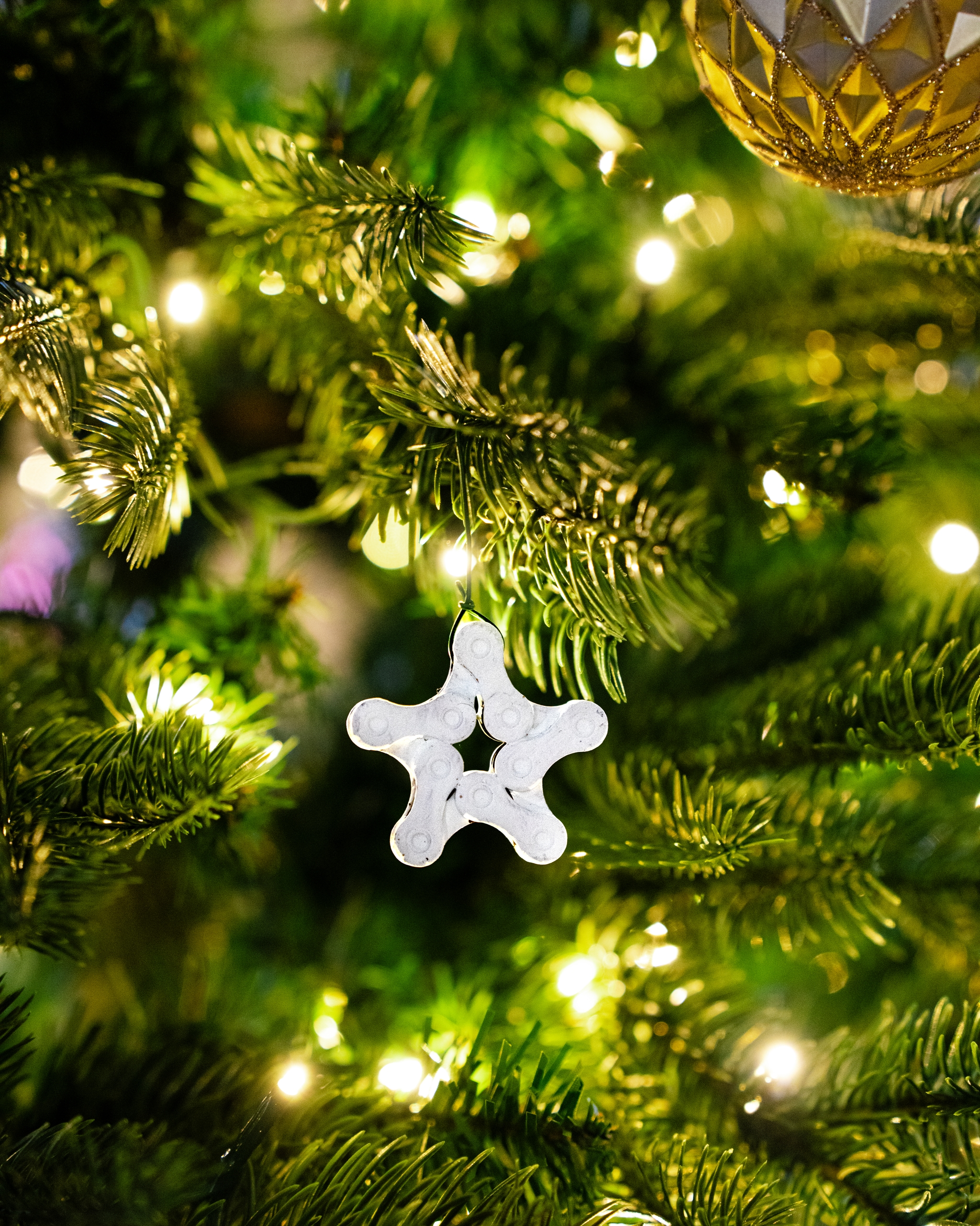 A festive star ornament hangs on a illuminated Christmas tree branch