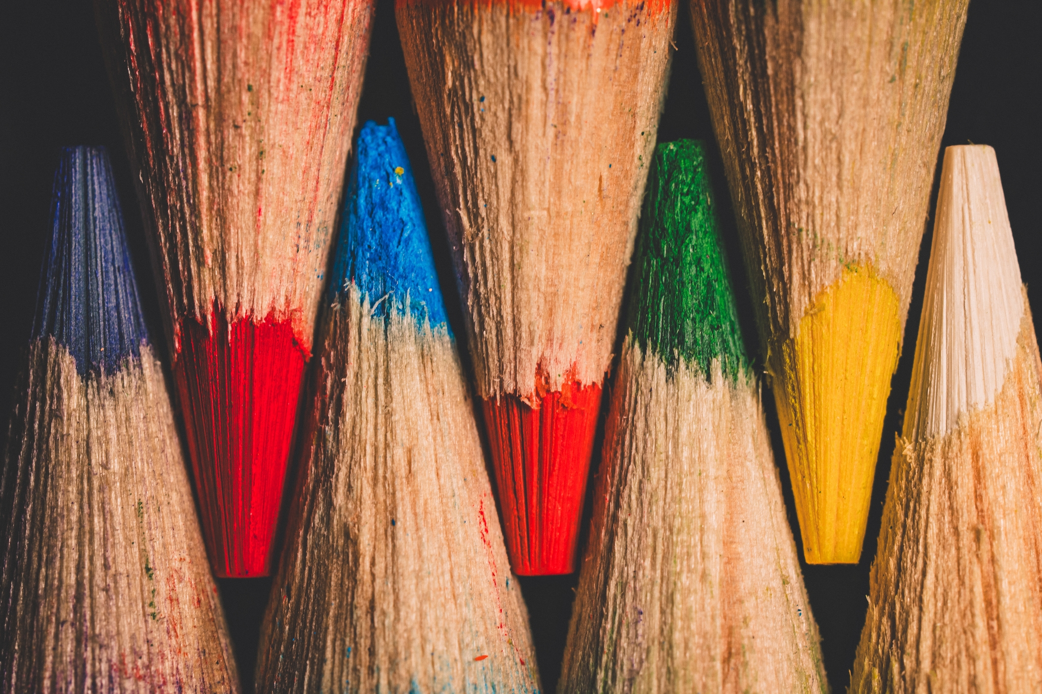 Close-up of the tips of colored pencils arranged in a row, displaying various colors like red, blue, green, yellow, and white