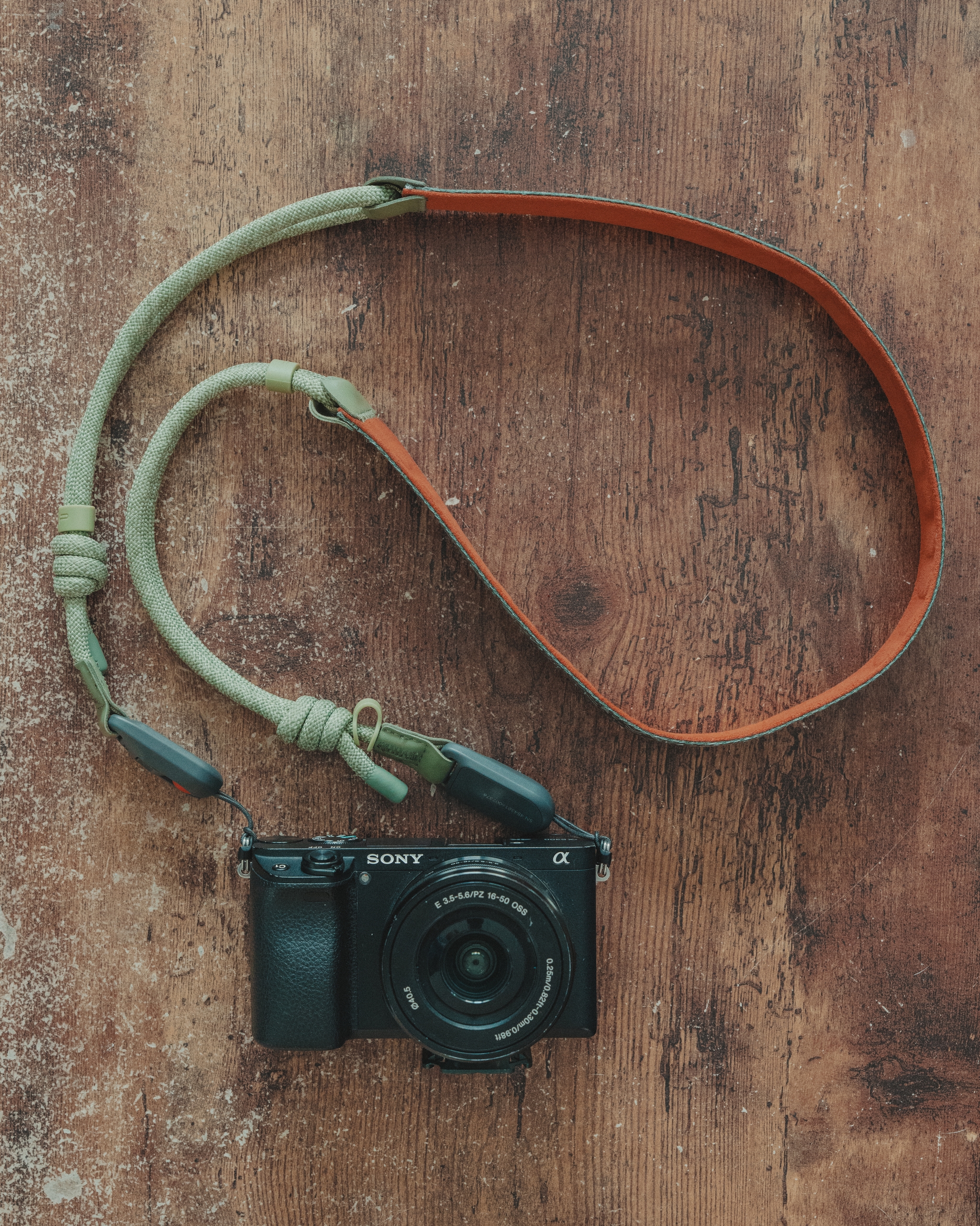 A camera with a braided strap on a wooden surface