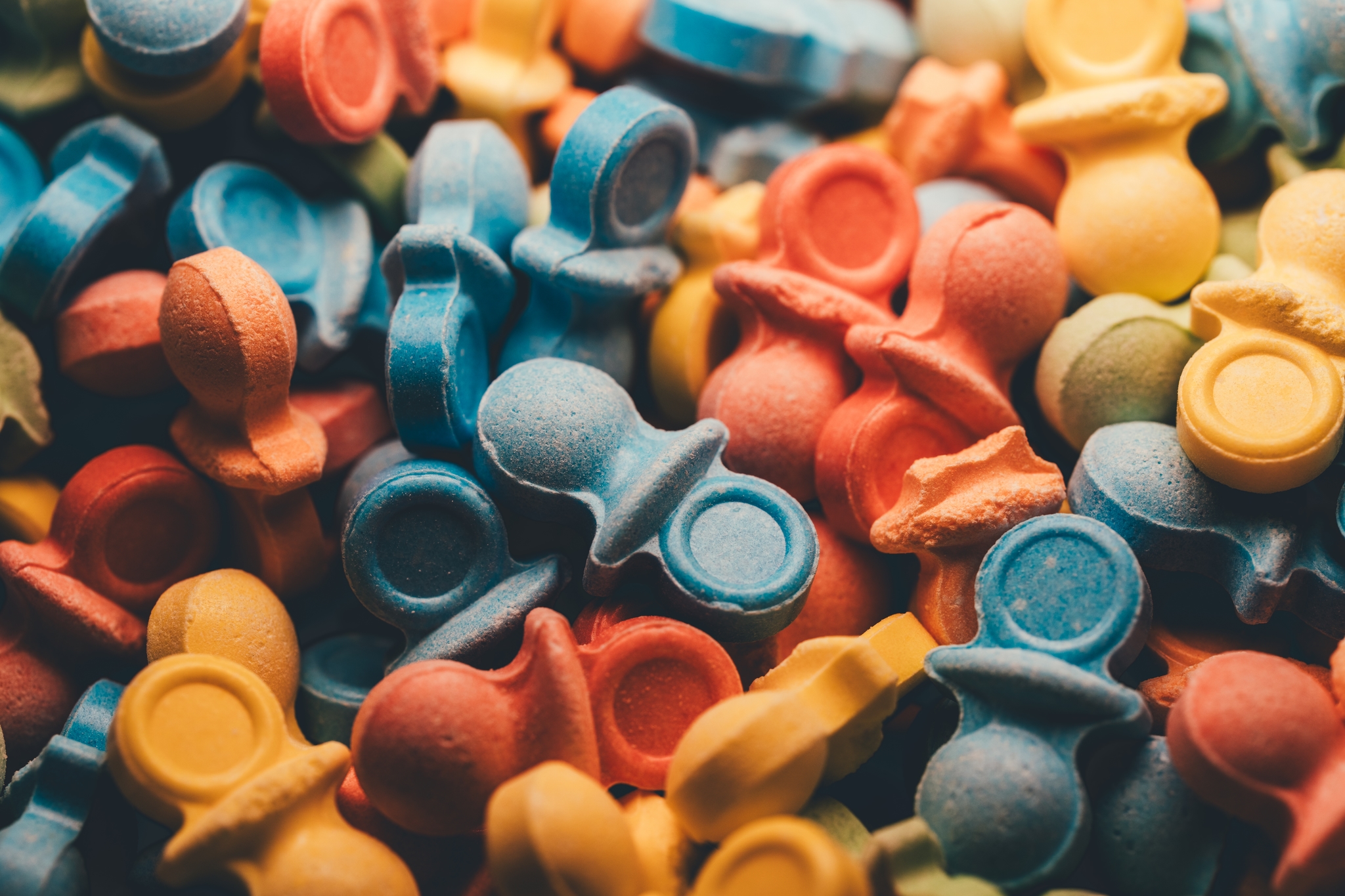 A close-up view of colorful candies in diverse shapes and colors forming a vibrant, chaotic pattern