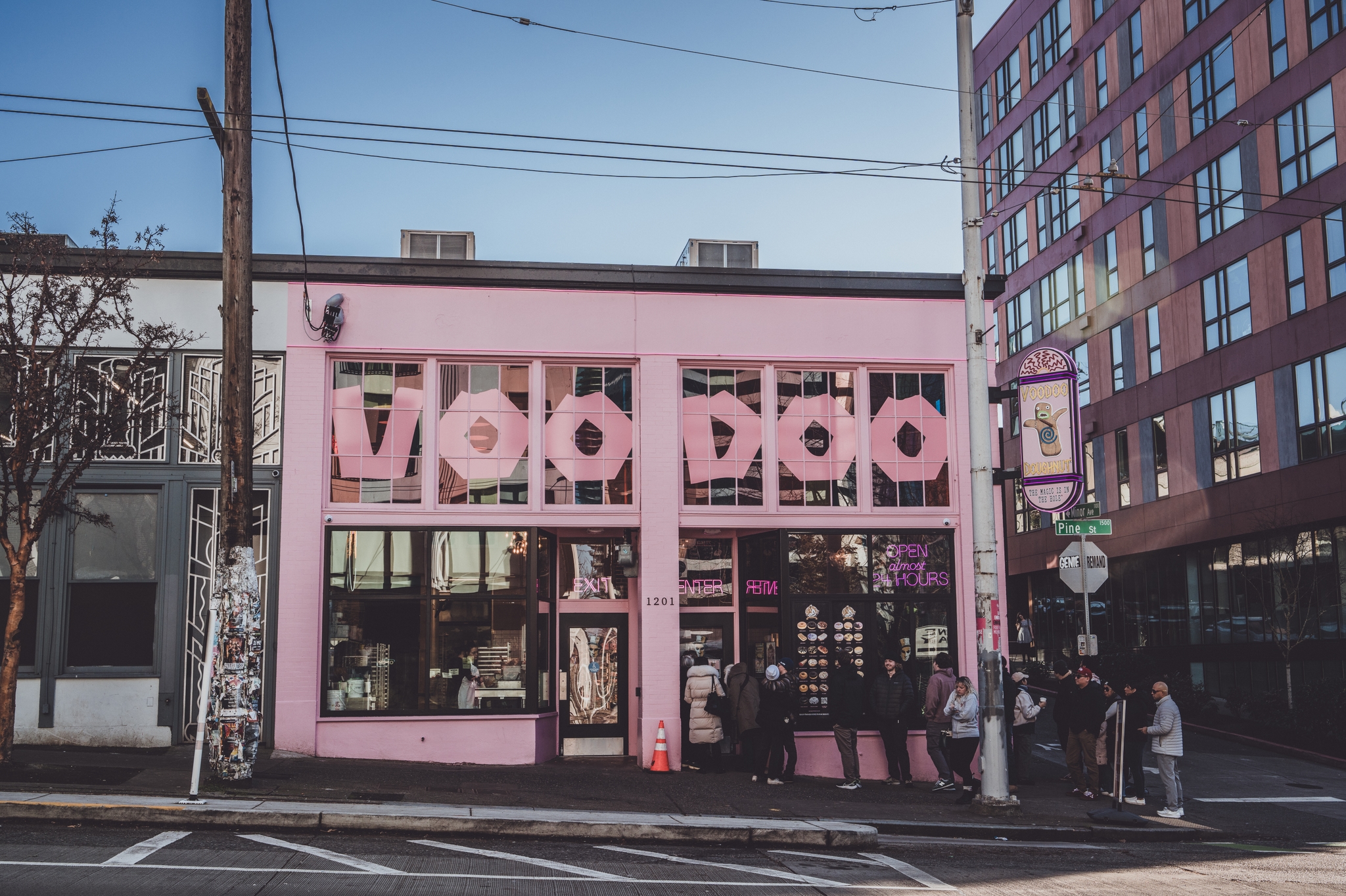 A pink building with large VOODOO letters on the facade, located on a street corner with people gathered outside