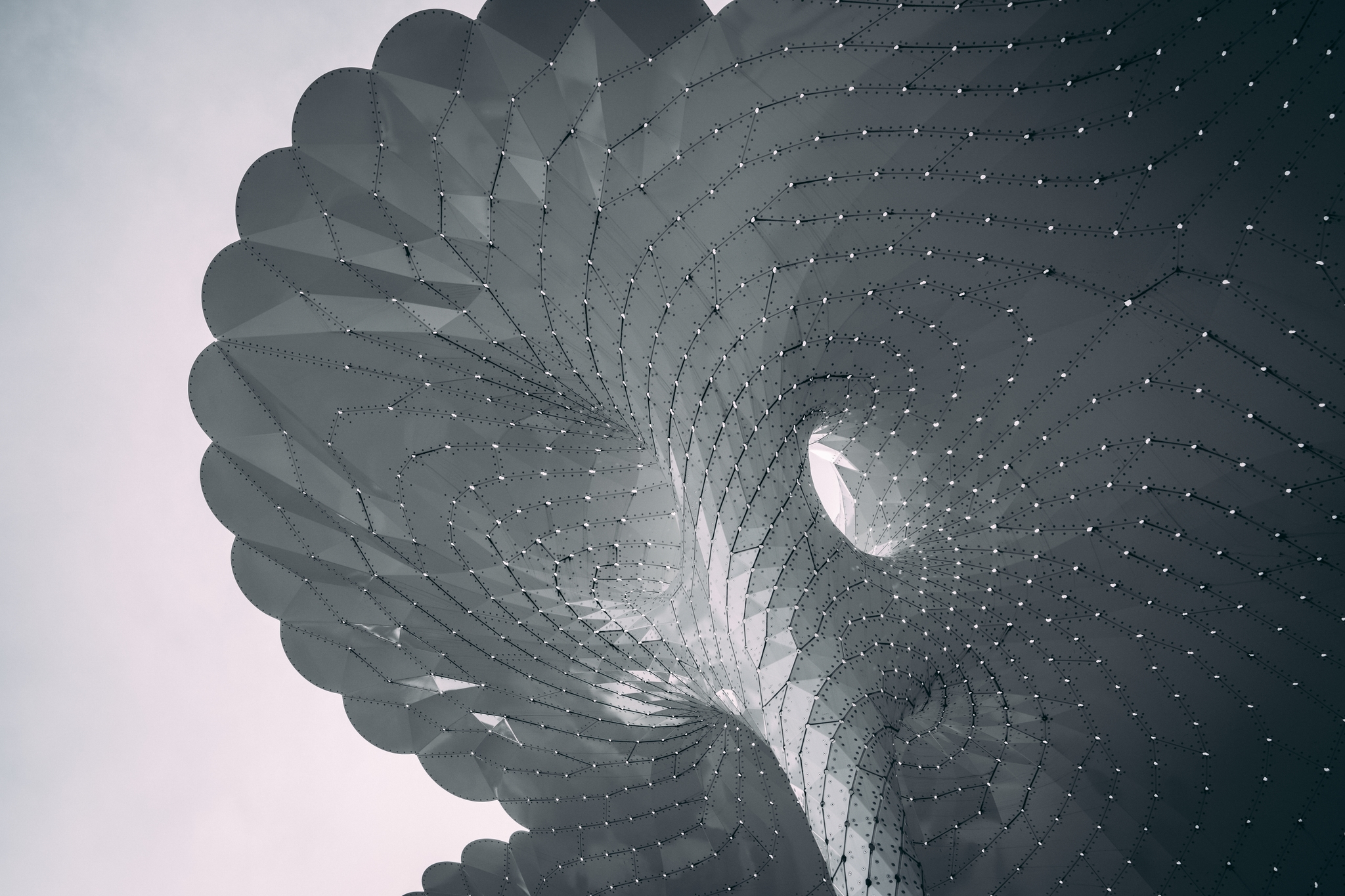 A large, abstract architectural structure with a honeycomb pattern and curved, overlapping surfaces, creating a dramatic and futuristic appearance