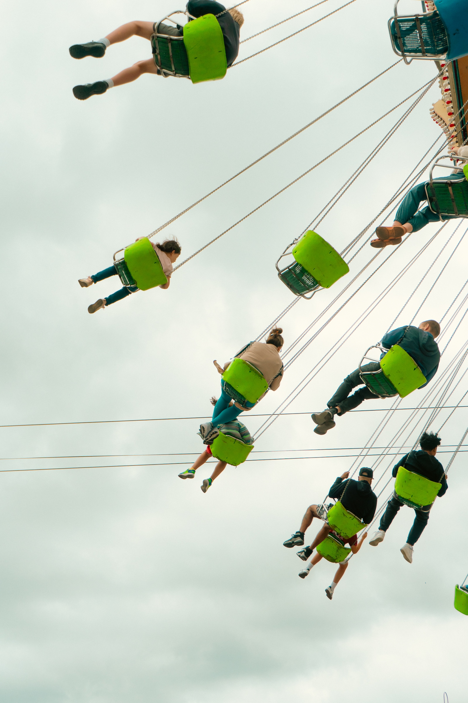 People enjoying a swing ride at an amusement park, with cloudy skies in the background