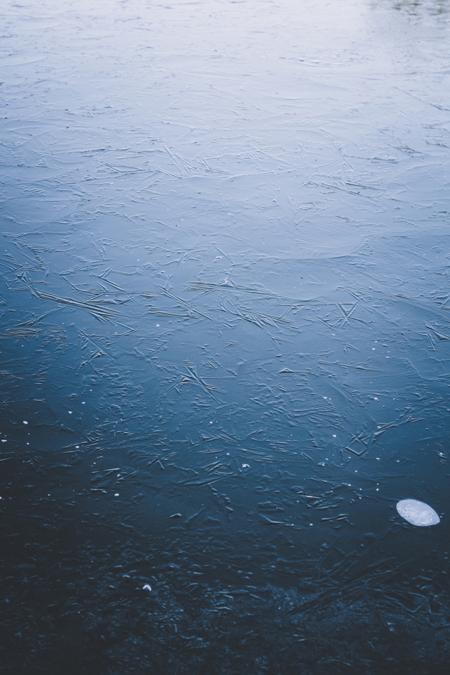 A frozen body of water with a smooth, icy surface and a small white object near the bottom right corner