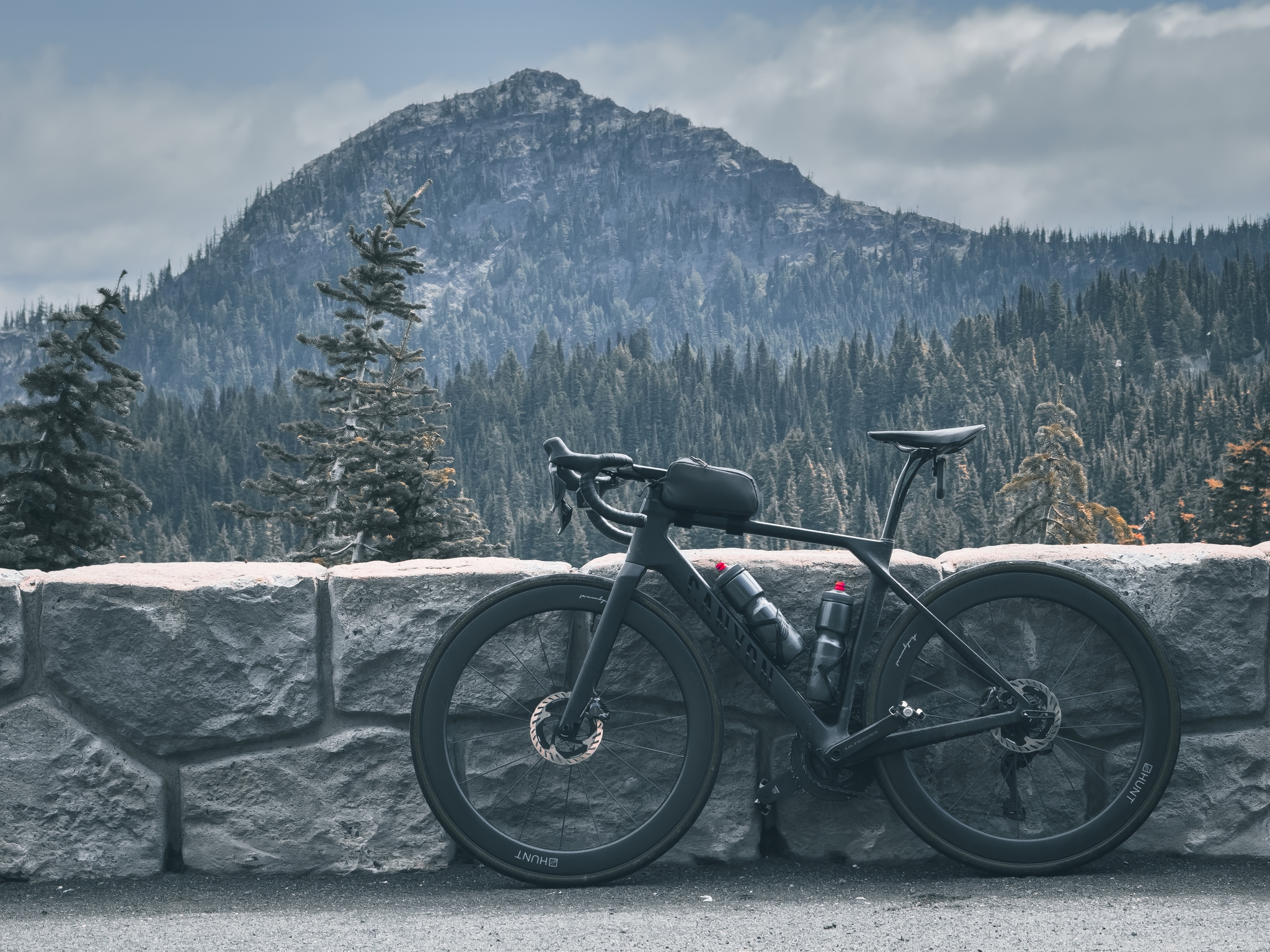 A bicycle is parked against a stone wall with a mountainous landscape in the background