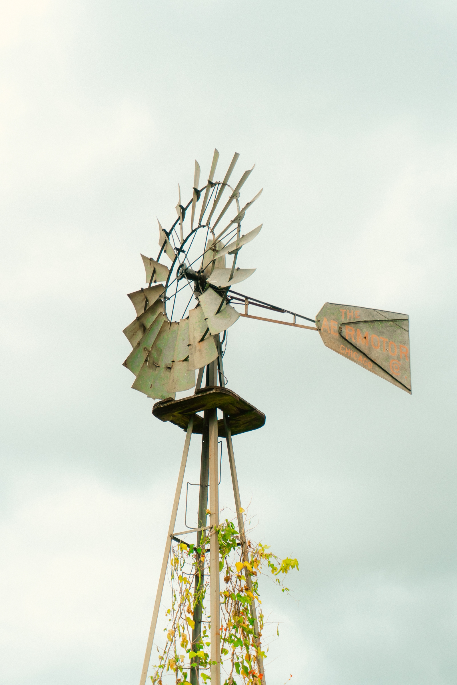 An old-fashioned metal windmill with a partly rusted appearance against a cloudy sky