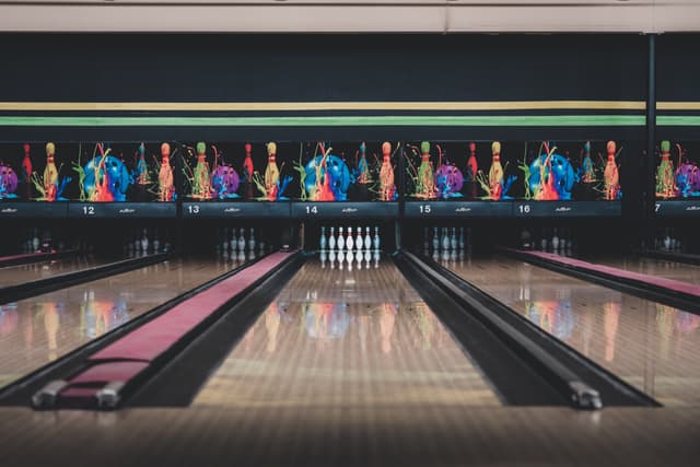 A bowling alley with multiple lanes, featuring colorful bowling pins arranged at the end of each lane