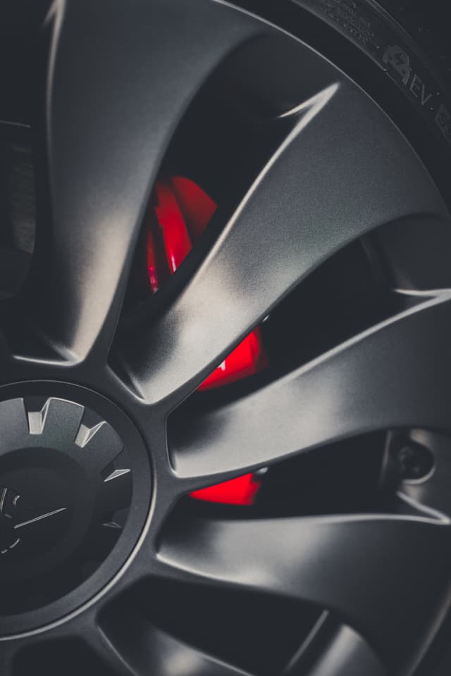 A close-up of a tesla uberturbine wheel with a sleek, metallic design and visible red brake calipers