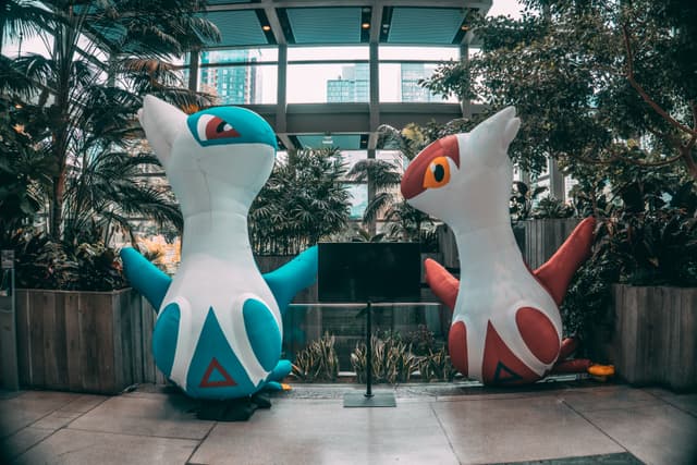 Two large Pokemon sculptures in a garden setting within a modern building