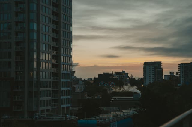 Silhouetted city skyline under a fading sunset with tall buildings and soft clouds