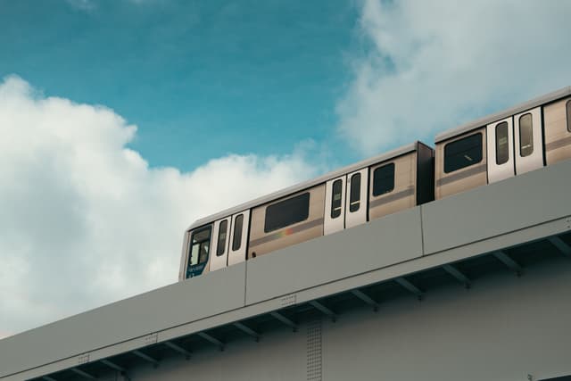 A train traveling on an elevated track against a backdrop of a partly cloudy sky
