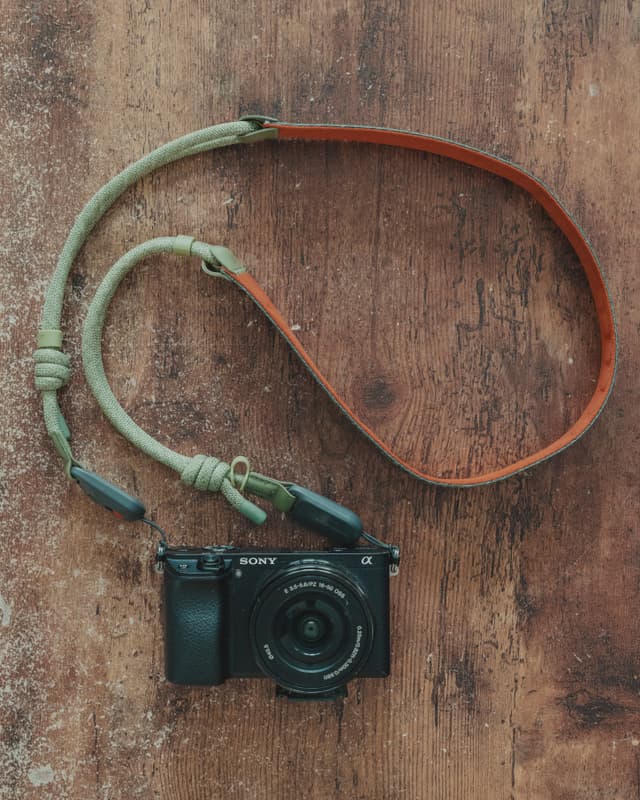 A camera with a braided strap on a wooden surface
