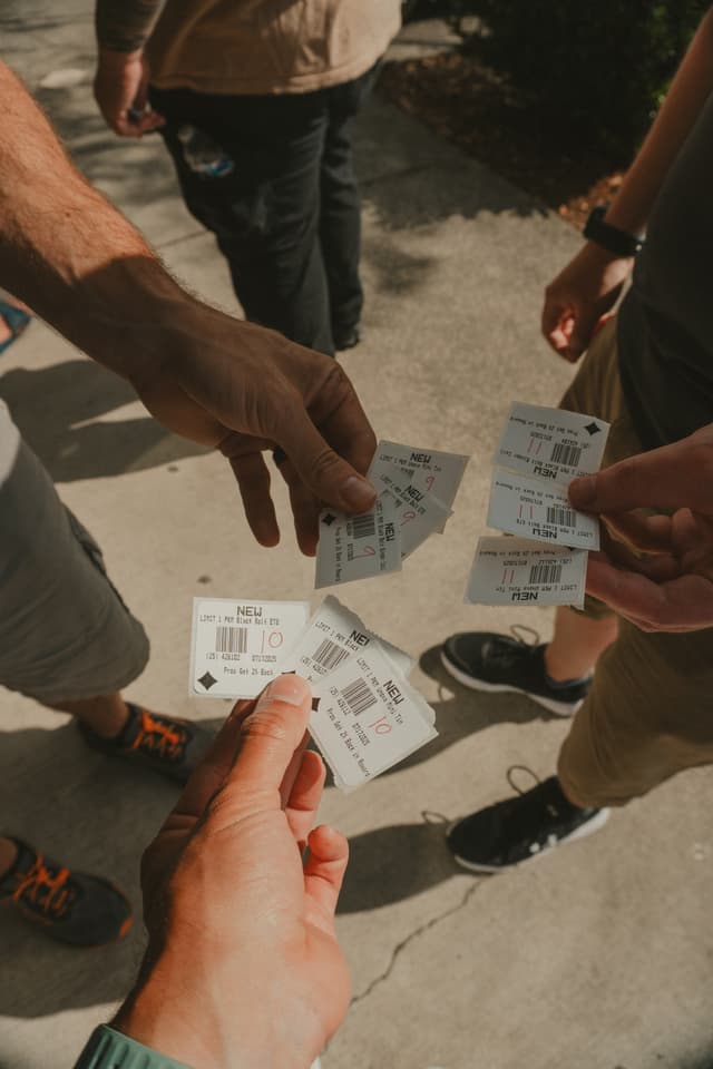 Several people holding and exchanging tickets outdoors, with a focus on their hands and the tickets