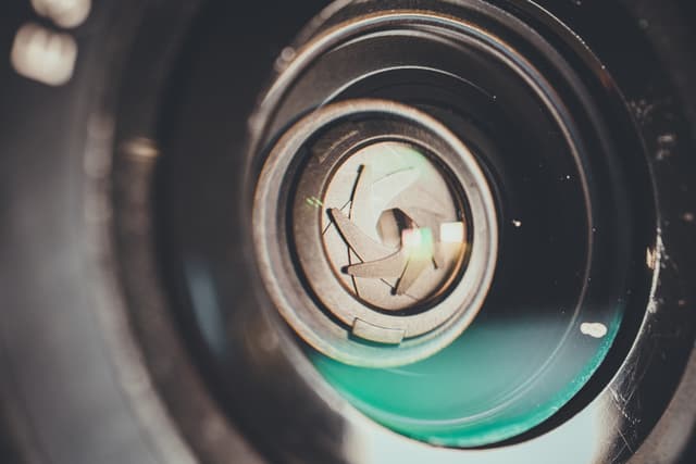 A close-up of a camera lens with visible aperture blades