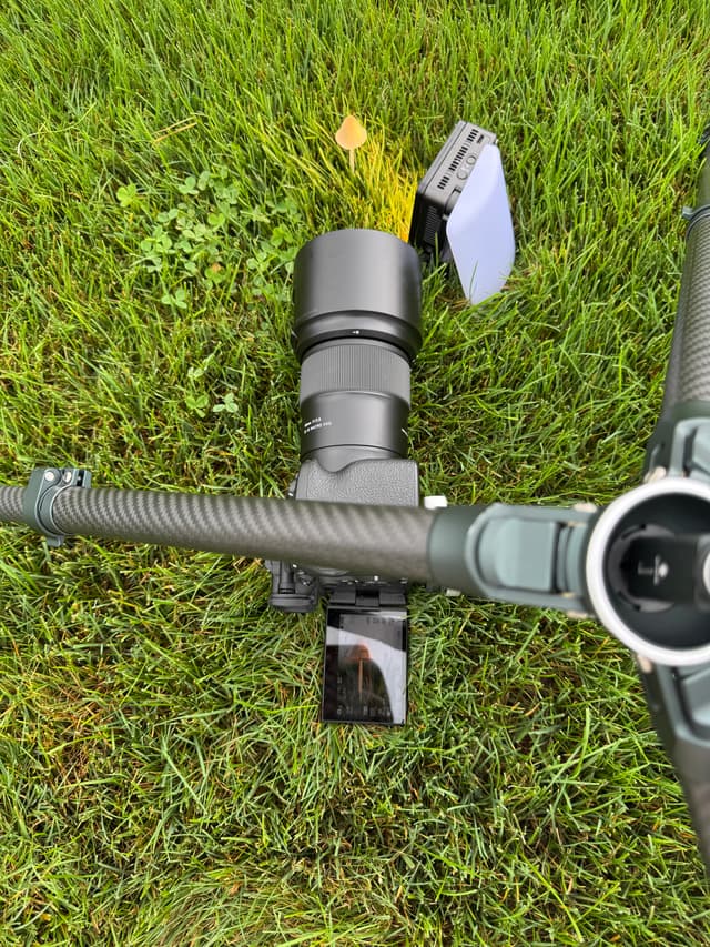 A tripod with a camerais positioned on grass, taking a macro photo of a mushroom