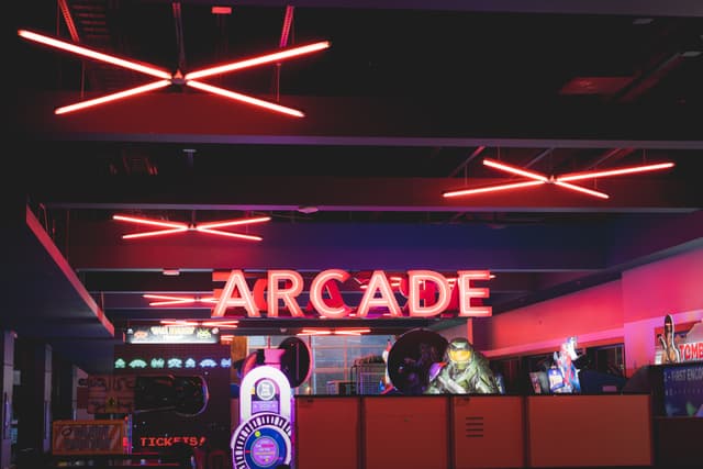 A dimly lit arcade with neon lights and various gaming machines
