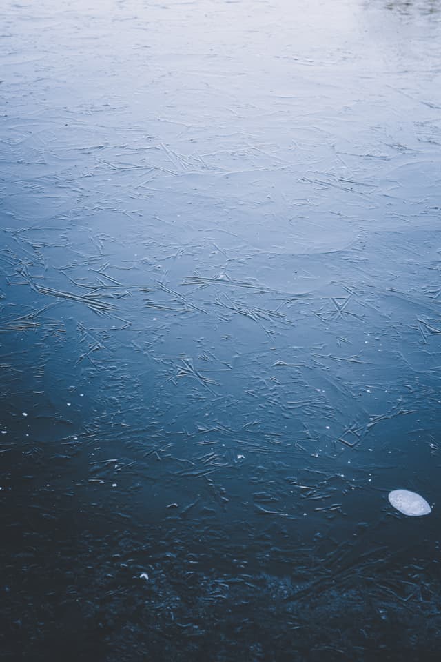 A frozen body of water with a smooth, icy surface and a small white object near the bottom right corner