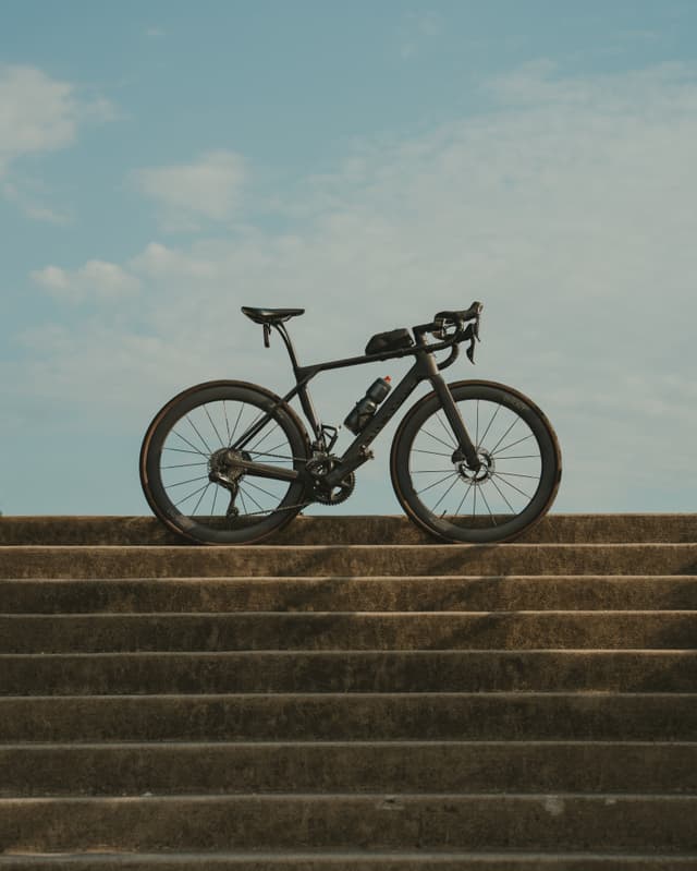 A bicycle is positioned on a set of concrete steps against a backdrop of a partly cloudy sky