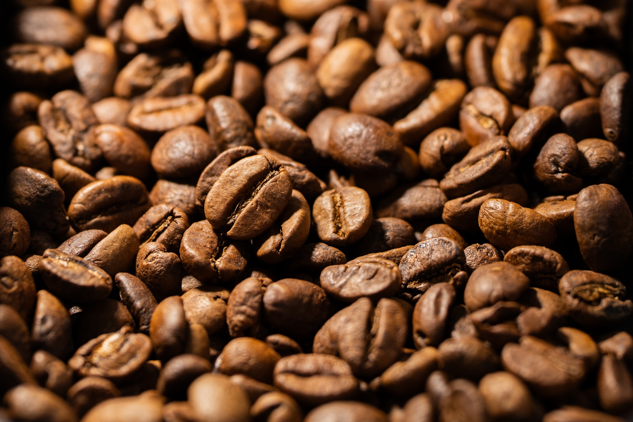 A close-up of roasted coffee beans with a rich, brown color and varied textures