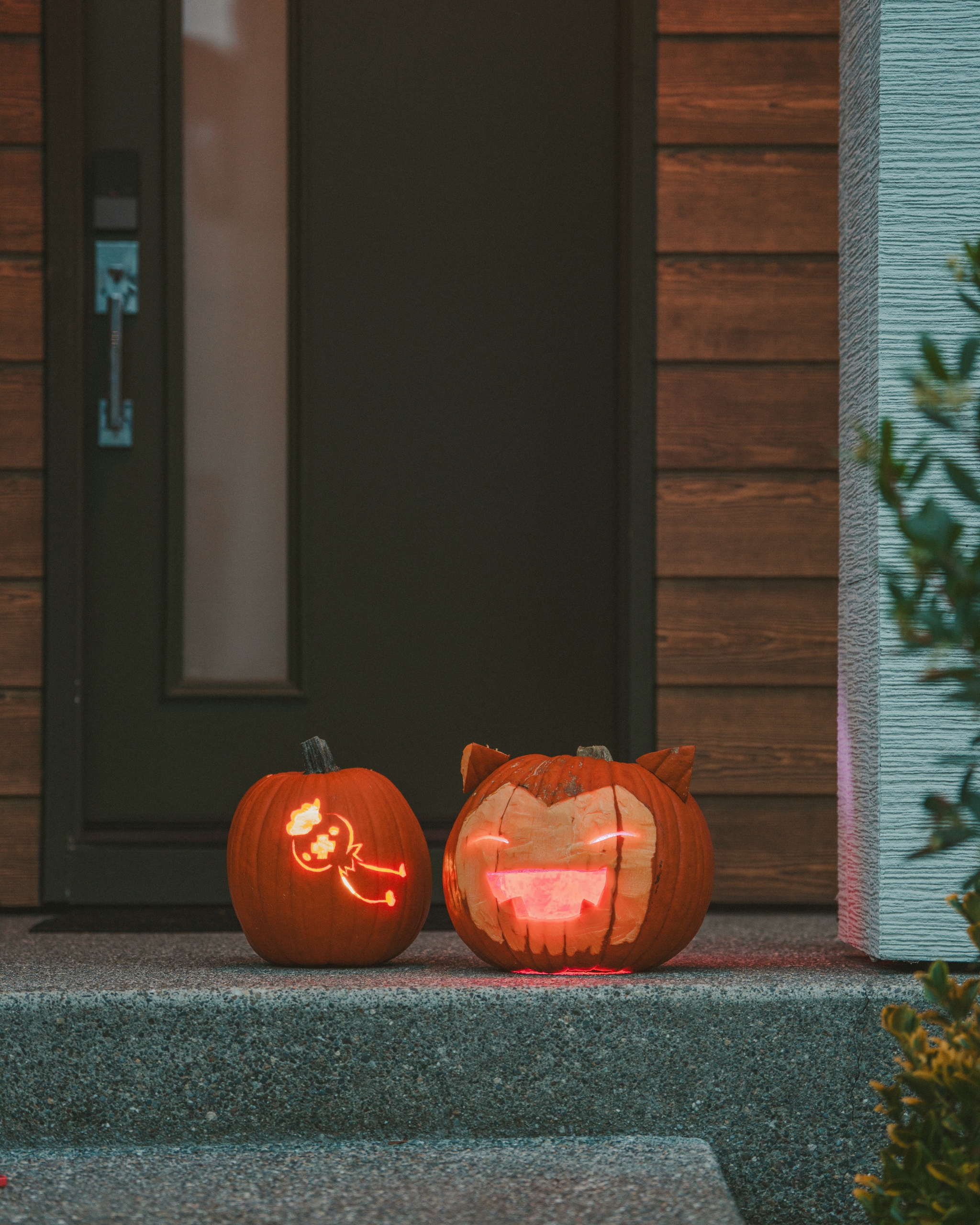 Two carved jack-o-lanterns glowing on a porch at night